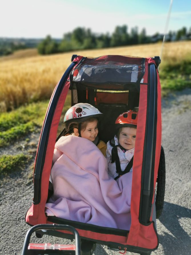 To barn som sitter i en rød Nordic Cab Explorer sykkelvogn