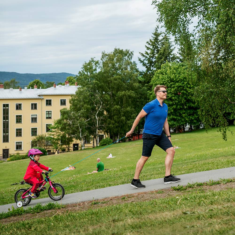 far trekker barn på sykkel med kidreel